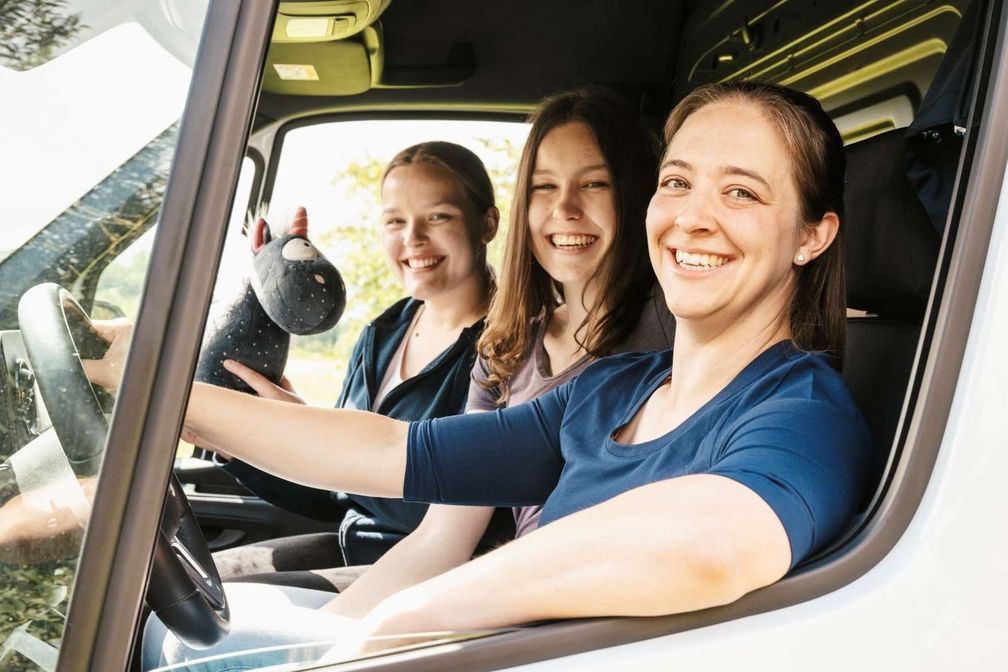 Team sitzt in einem Waagen und lächeln - Farina Fuest am Steuer